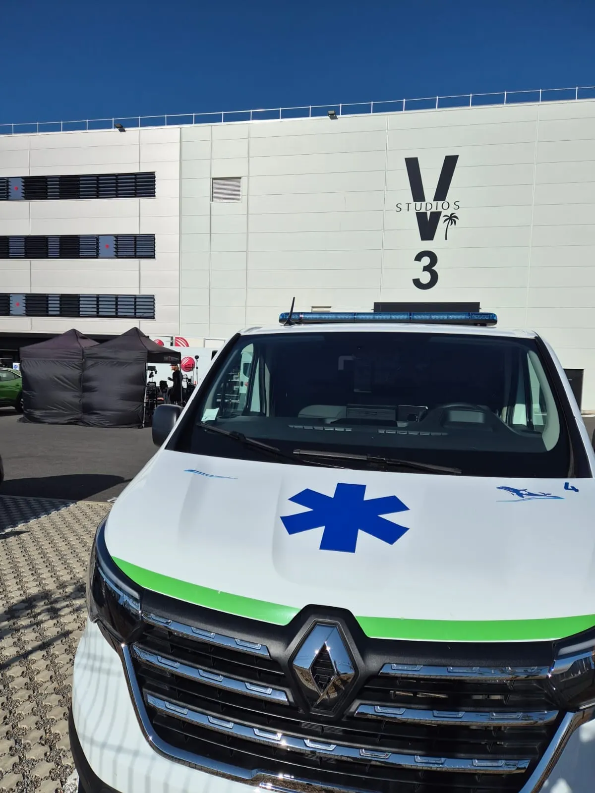 Ambulance d'Ambulances Santé stationnée devant un bâtiment de studios de tournage